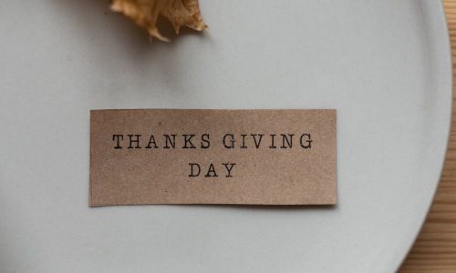 A label that says Thanksgiving Day on a white plate, the label is made from Thanksgiving crafts